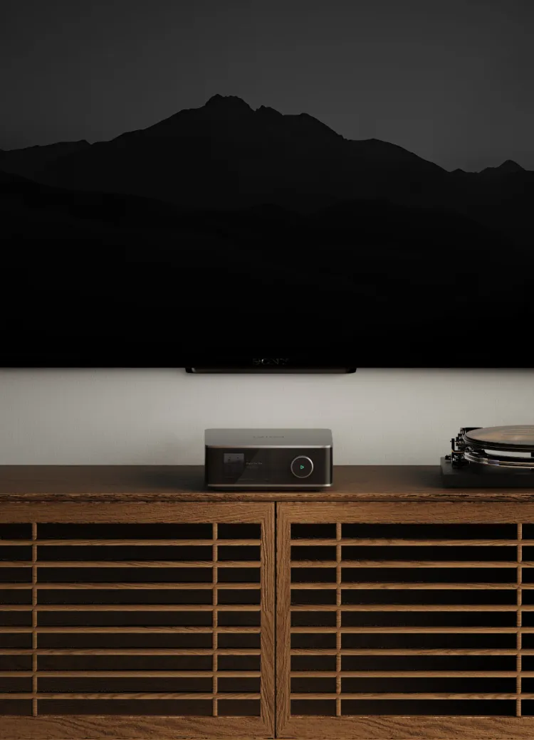 WiiM Amp Ultra sous un téléviseur, entre deux enceintes colonnes