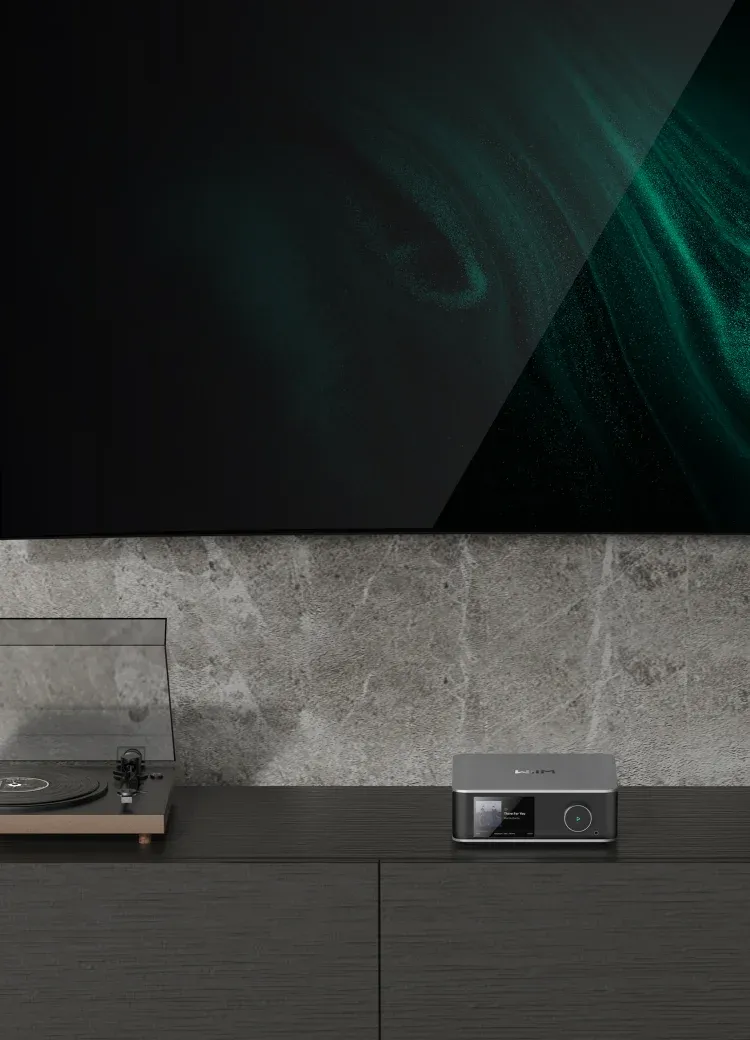 WiiM Ultra posé sur un meuble TV à côté d’une platine vinyle